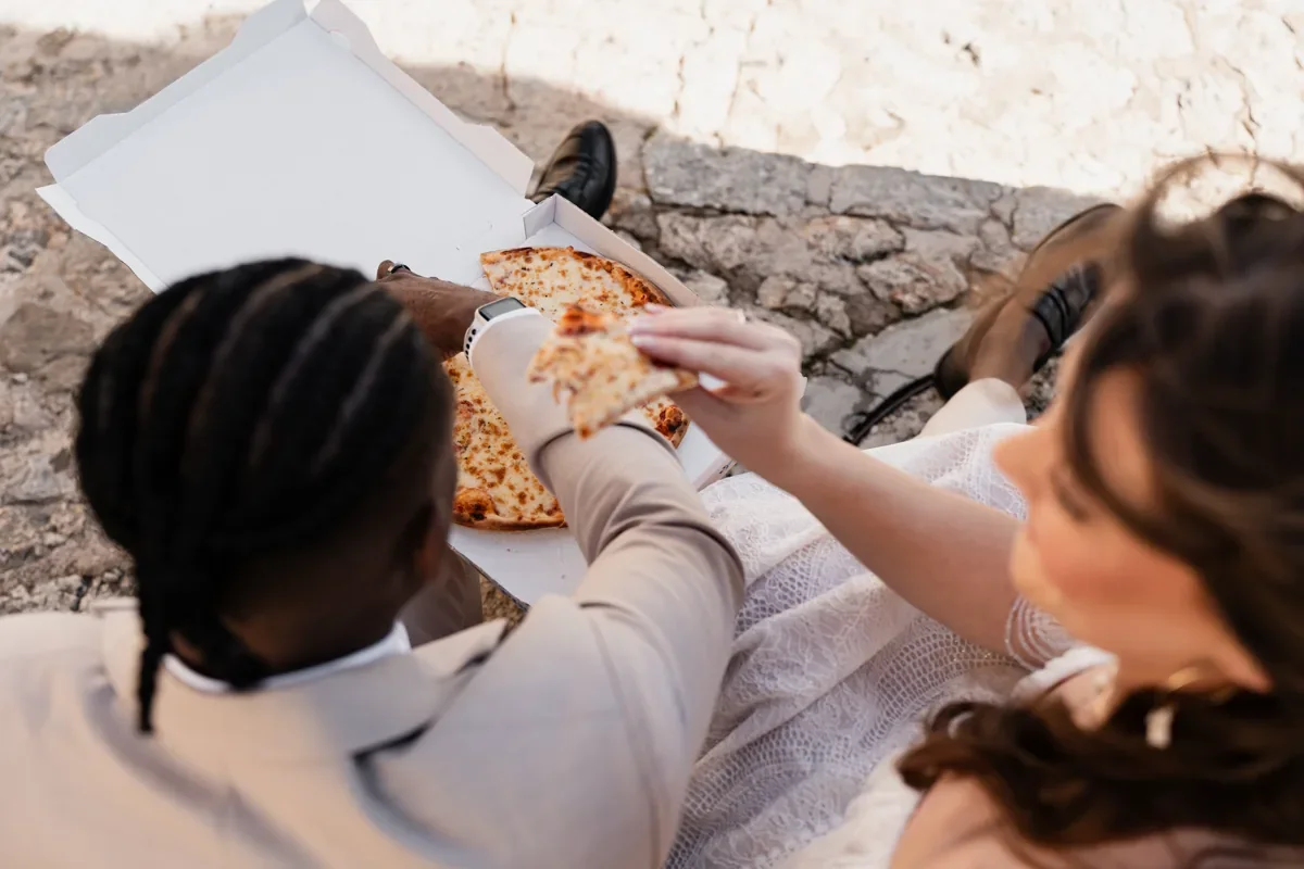 Brautpaar teilt eine Pizza auf den Steinstufen