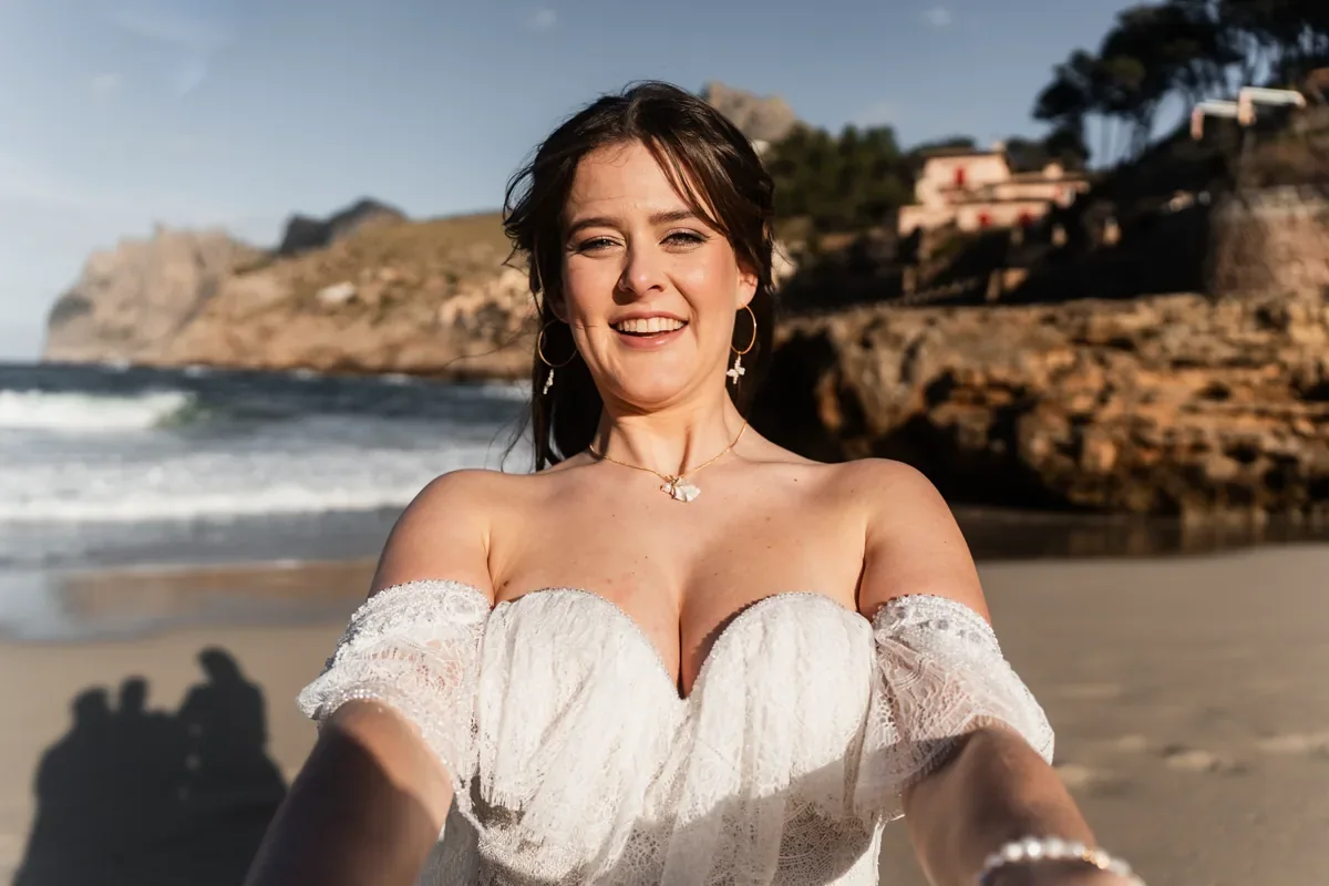 Braut lacht vor dem Meer in die Kamera