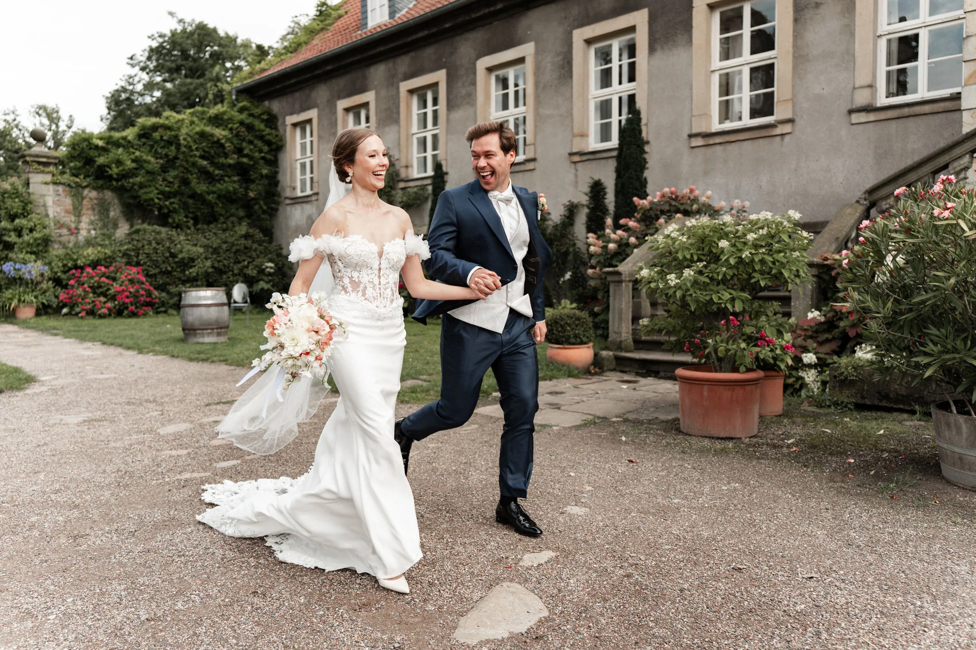 Brautpaar steht mit einem klassischen Wagen im Hof