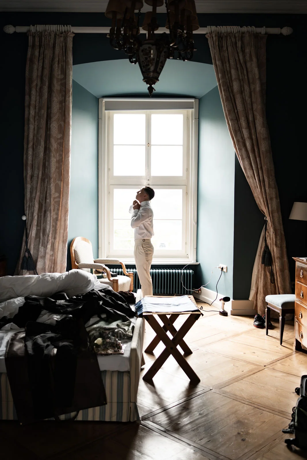 Bräutigam macht sich vor Fenster zurecht