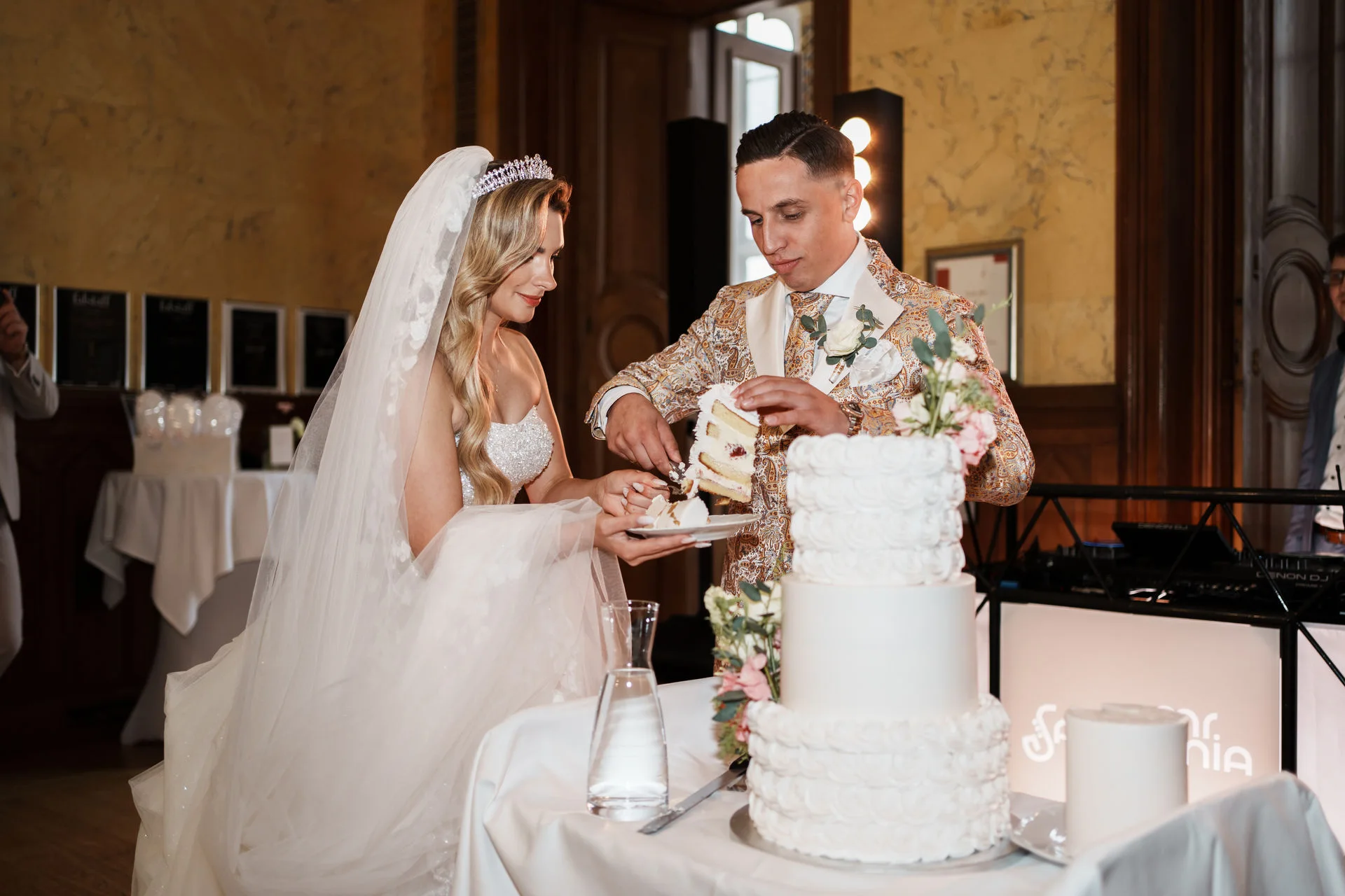 Brautkleid schneidet die Torte an
