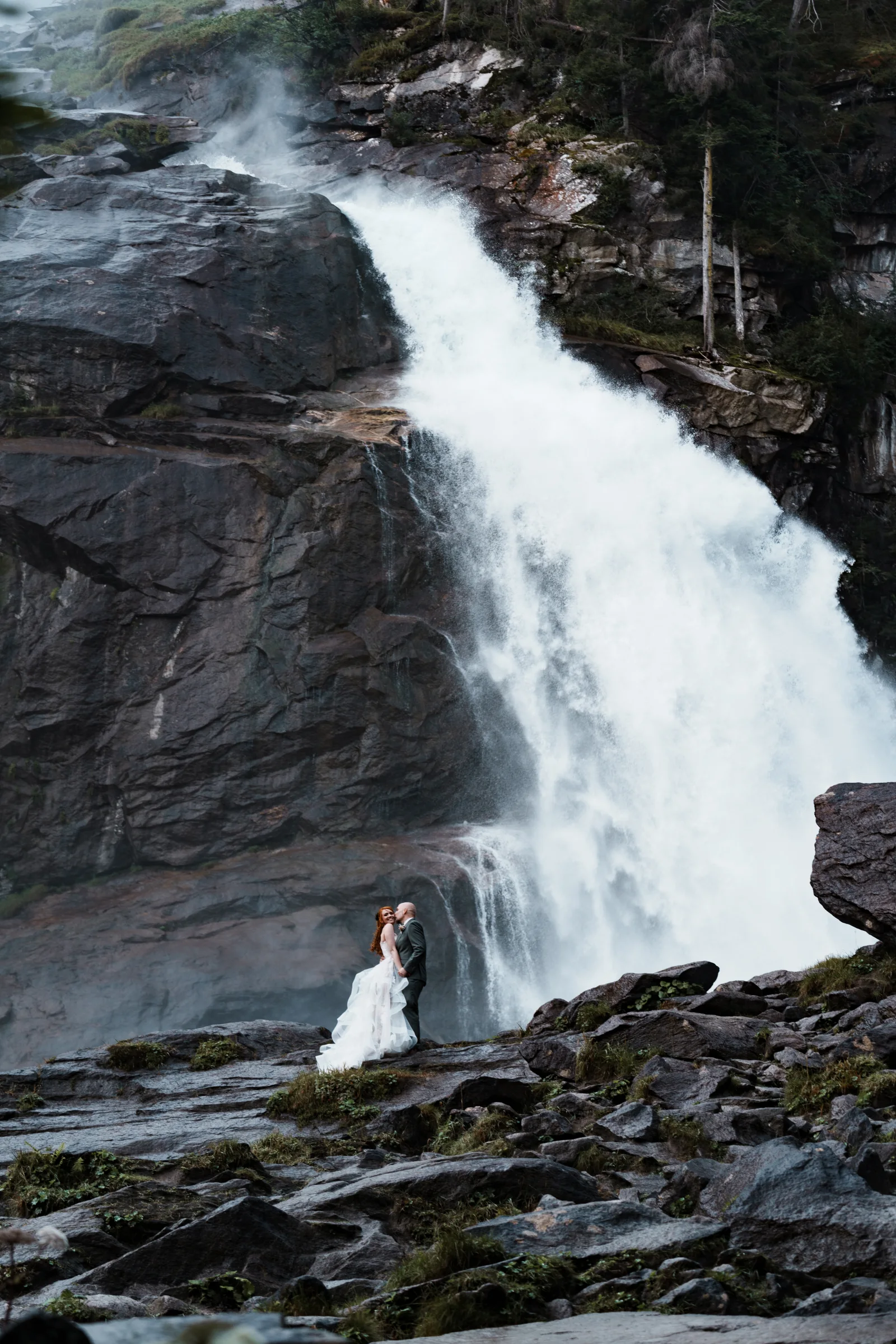 Brautpaar umarmt sich vor einem Wasserfall